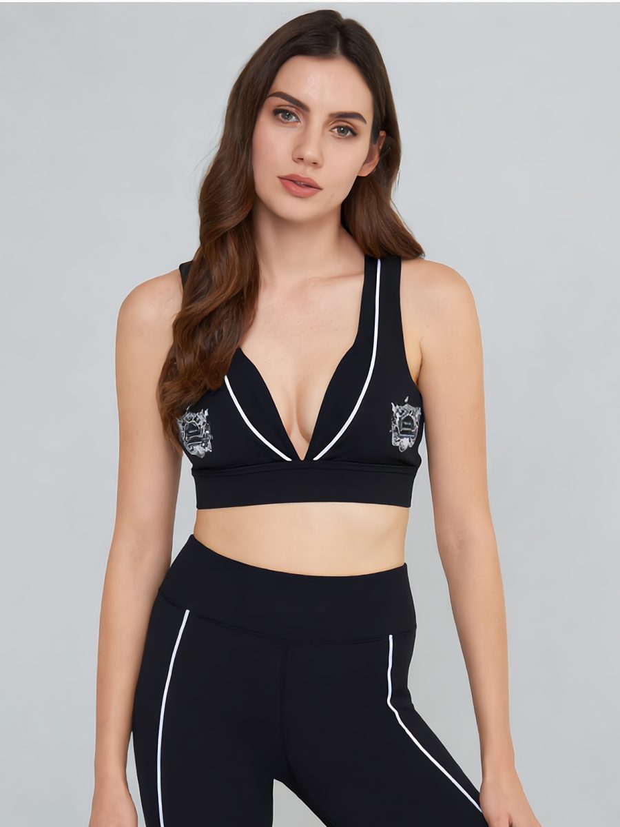 Model in a black sports bra and leggings with white piping