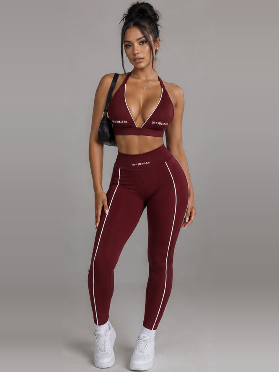Model in a burgundy halter sports bra and matching leggings with white piping