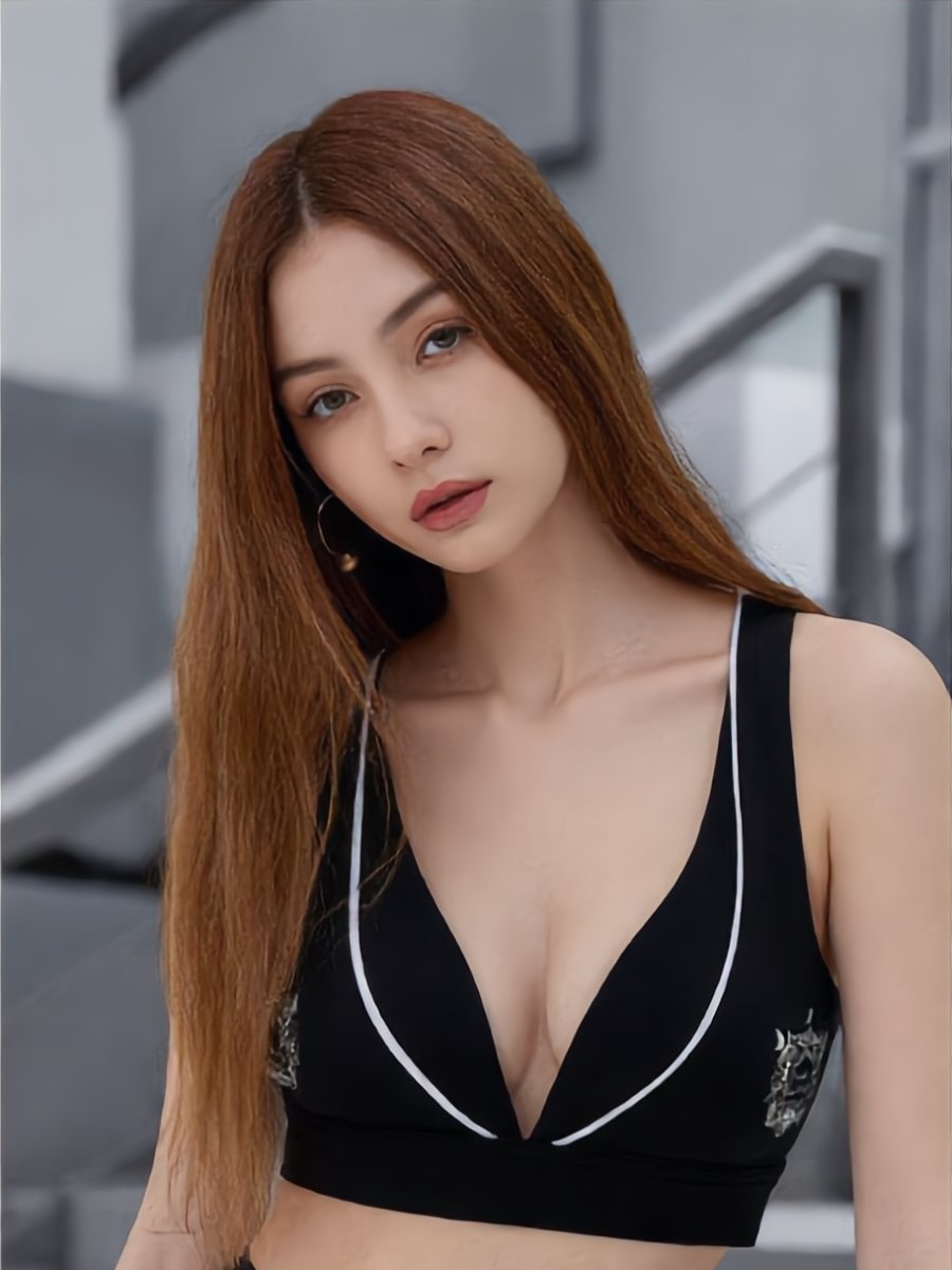 Model in a black sports bra with white piping and crest print