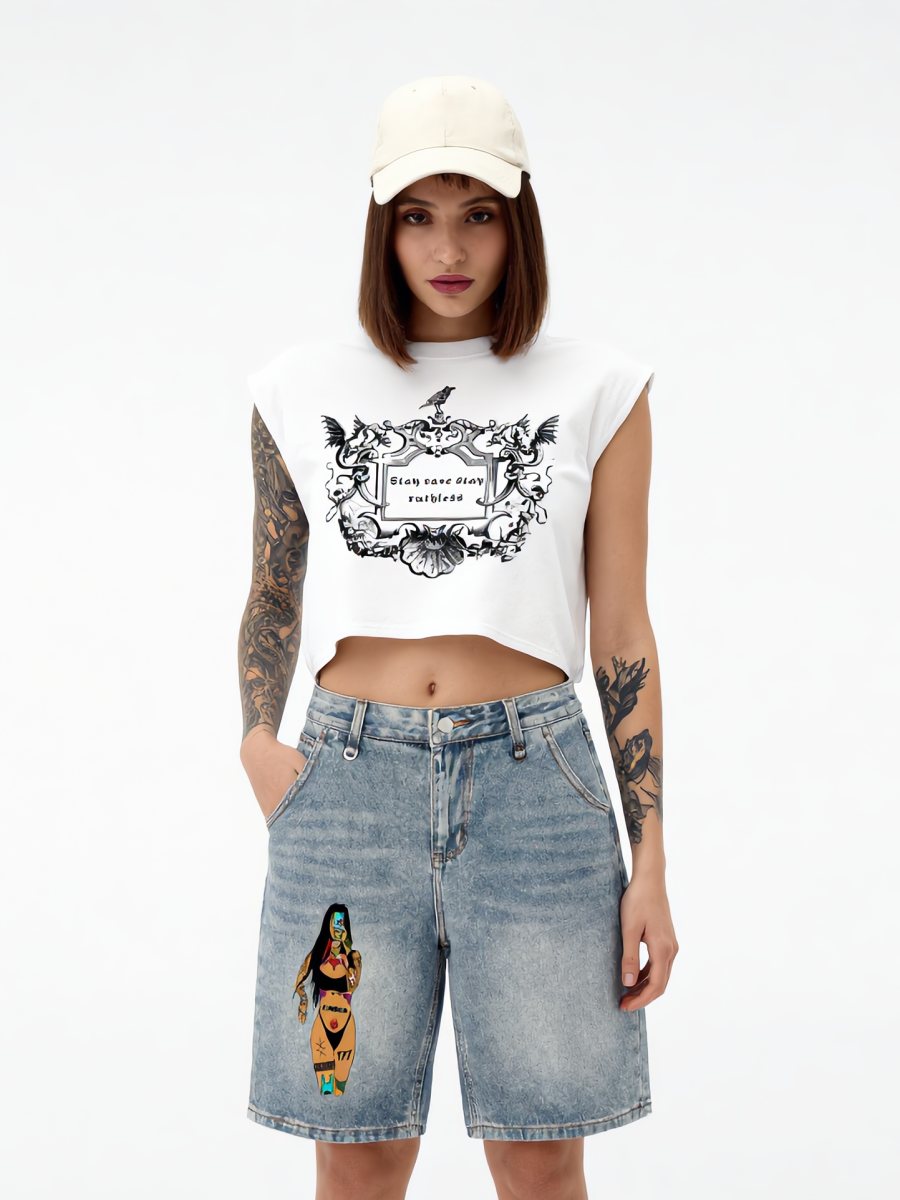 Model in a cap, cropped white crest tank and graphic denim shorts
